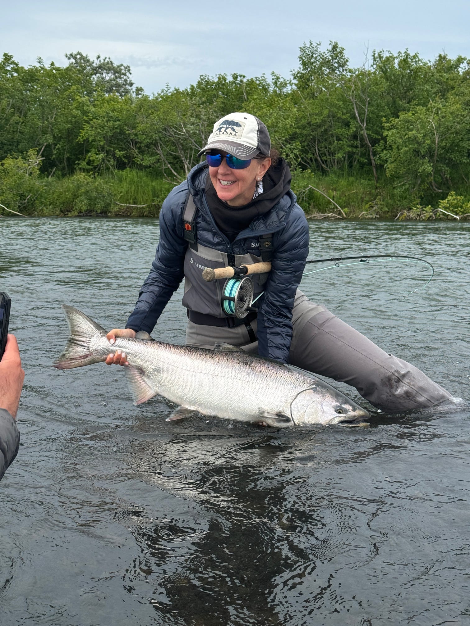 Angler proudly holds a massive king salmon caught while fly fishing an Alaskan river
