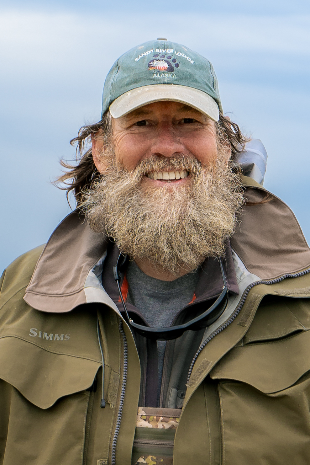 Close-up of smiling bearded angler wearing outdoor jacket