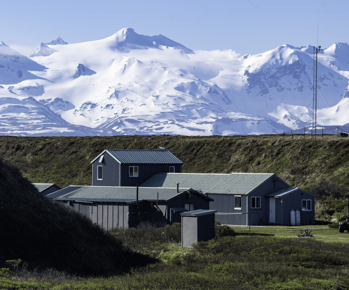 Remote Alaska fishing lodge with cabins beneath snow-covered mountains on the Aleutian Peninsula
