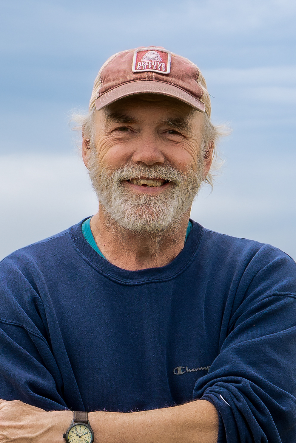 Close-up portrait of smiling older man with white beard wearing blue sweatshirt at Alaska fishing camp