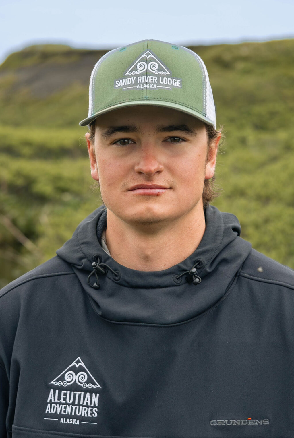 Close-up portrait of young man in dark hoodie at Alaska fishing camp