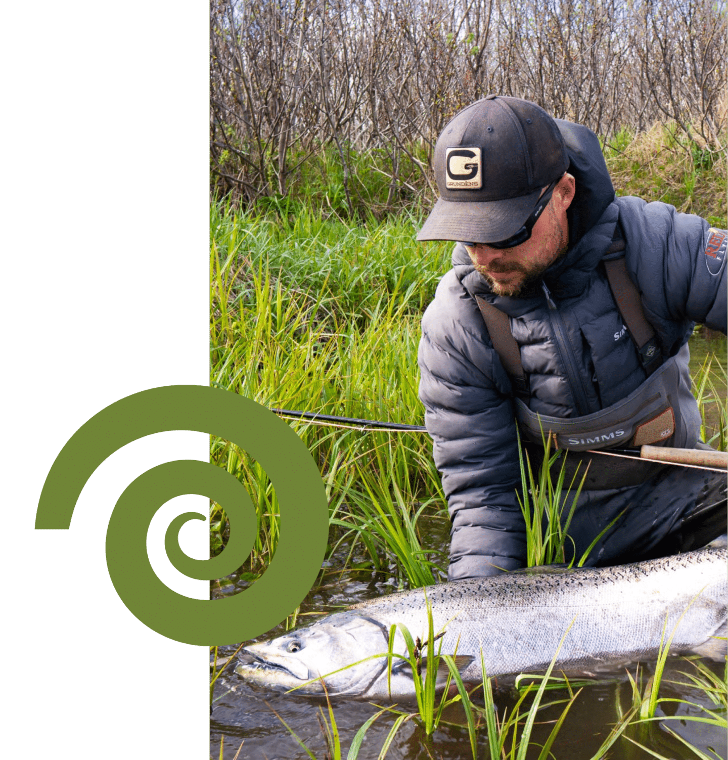 Angler kneeling in tall grass along Alaska riverbank while fishing