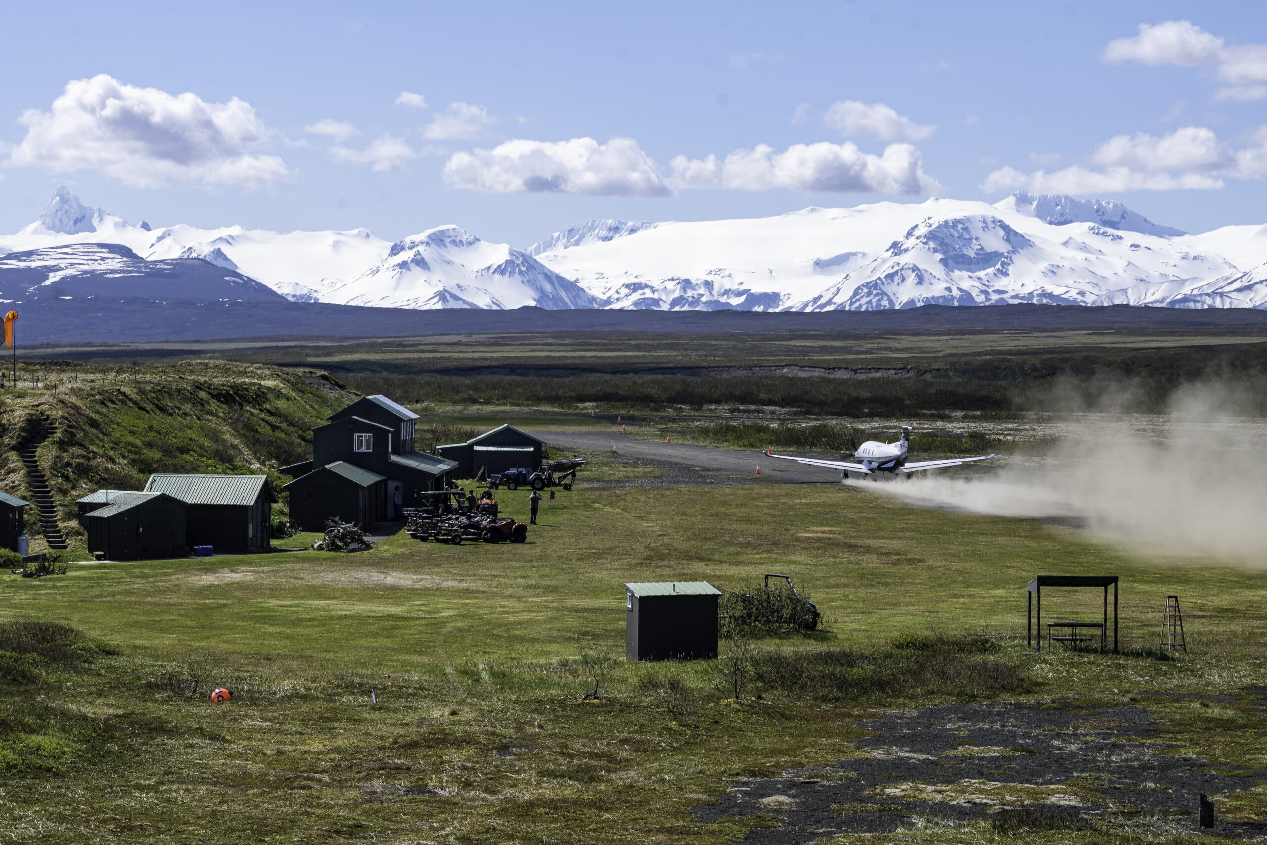 Small plane lands on remote Alaska airstrip with snow-covered mountains in view