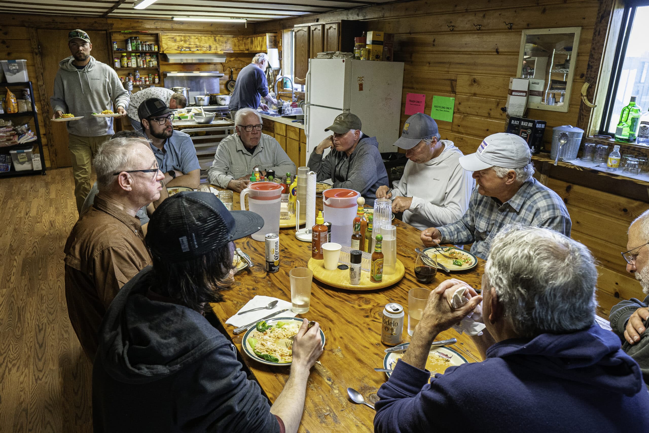 Guests enjoy a hearty group meal inside Sandy River Camp’s rustic Alaska lodge