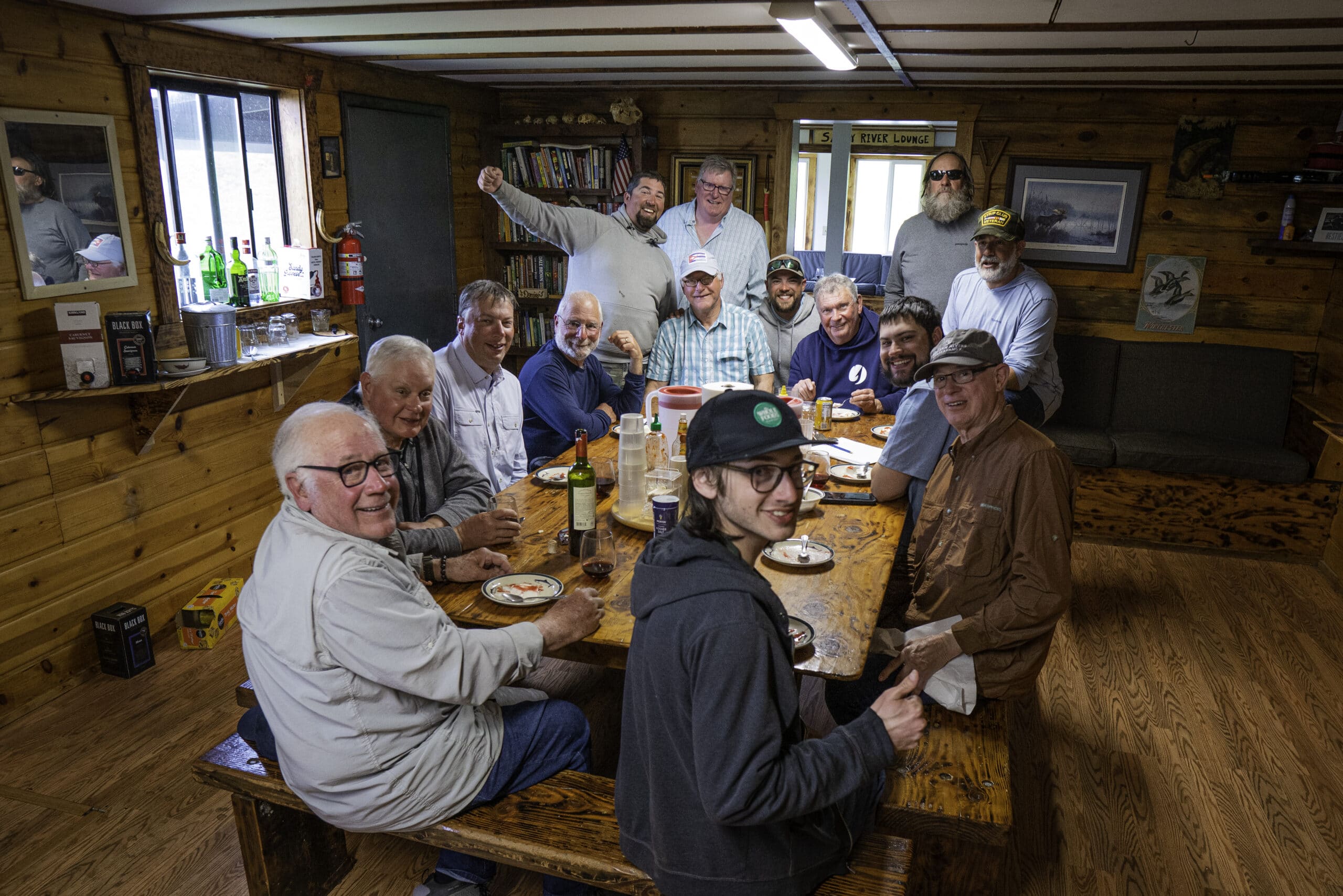 Anglers gather inside the lodge at Sandy River Camp, sharing stories after a day of Alaska fishing