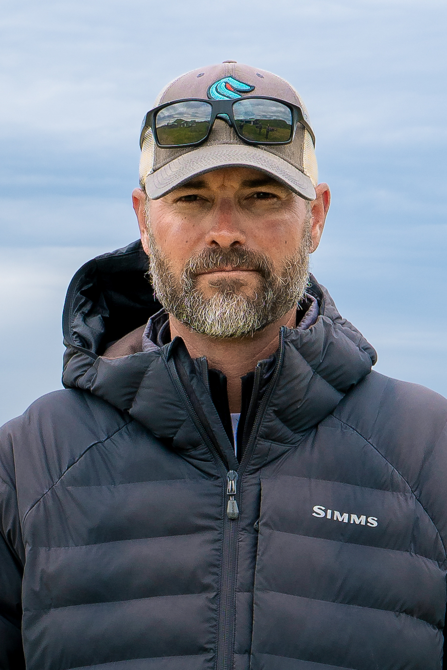 Close-up portrait of man with gray beard wearing black jacket at Alaska fishing camp