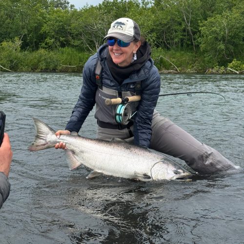 Angler proudly holds a massive king salmon caught while fly fishing an Alaskan river