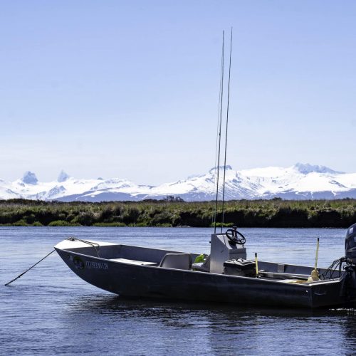 Fishing boat anchored on the river with Alaska’s snow-capped mountains in the background