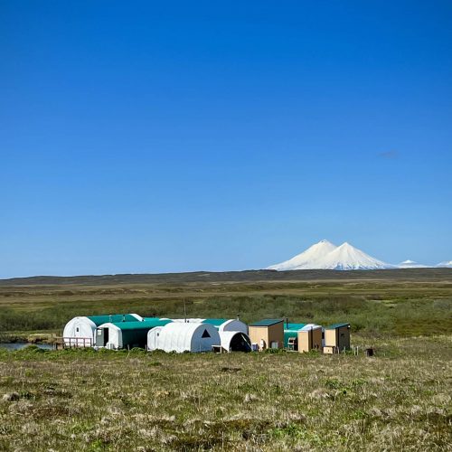 Remote Alaska fishing camp with snow-capped volcano in the background