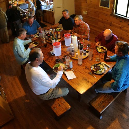 Guests enjoy a hearty dinner together inside the Alaska fishing camp lodge
