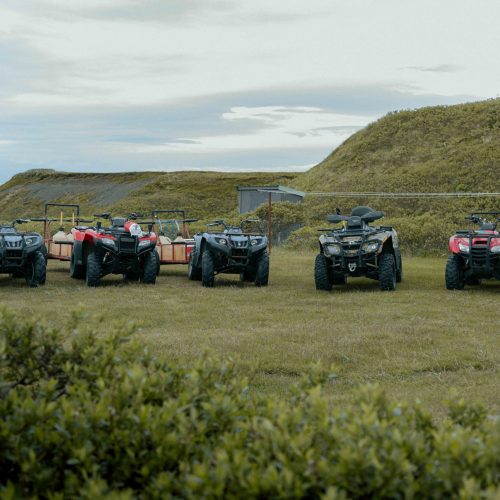 Row of ATVs with trailers parked on grassy field at Alaska fishing camp