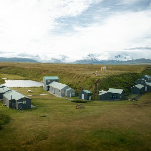 Remote Alaska fishing camp with cabins beside a stream and tundra, mountains in background