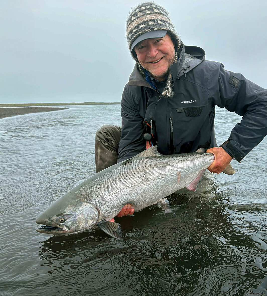 Angler holding a large silver salmon in shallow river water