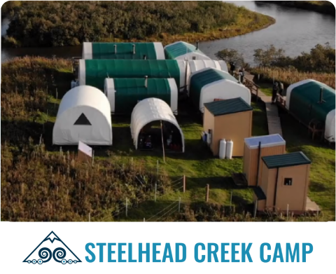 Aerial view of Steelhead Creek Camp with green and white tents near a winding creek